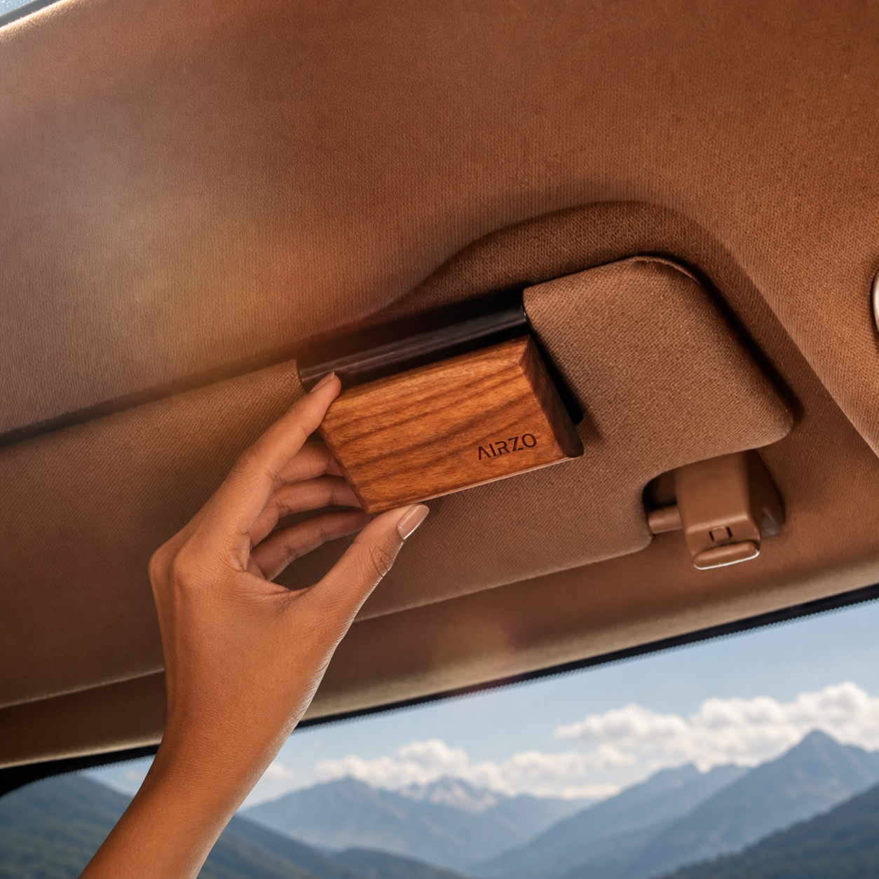 AIRZO Wood Car Freshener installed on a car sun visor with a mountain landscape visible through the windshield